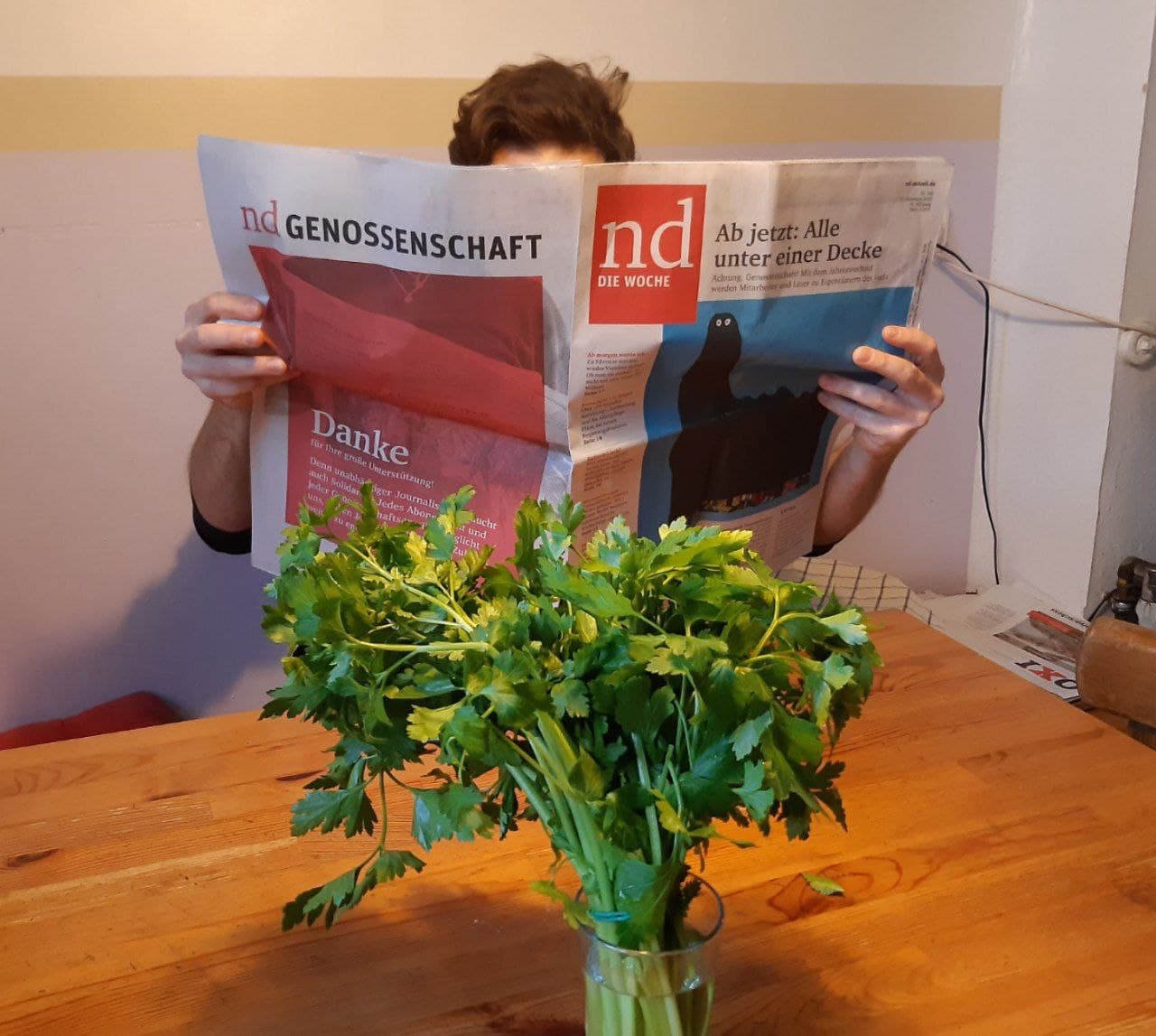 Eine Person liest eine Ausgabe der Tageszeitung nd.